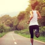 a foto mostra uma mulher correndo em uma estrada