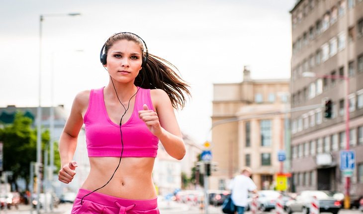 Mulher com fones de ouvido praticando corrida de rua dicas para a corrida de rua