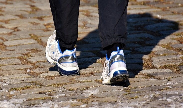 Imagem de uma pessoa caminhando calçando tênis Cuidados com os pés