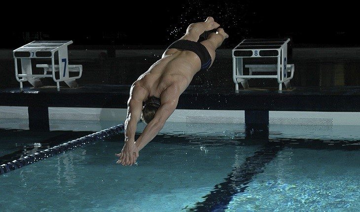 homem mergulhando na piscina com os braços esticados