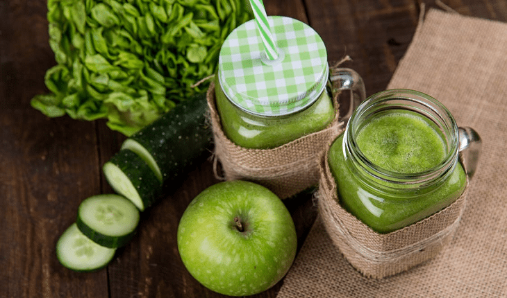 Receitas de sucos funcionais: suco detox. Na foto, um suco verde cercado por maçã e pepino