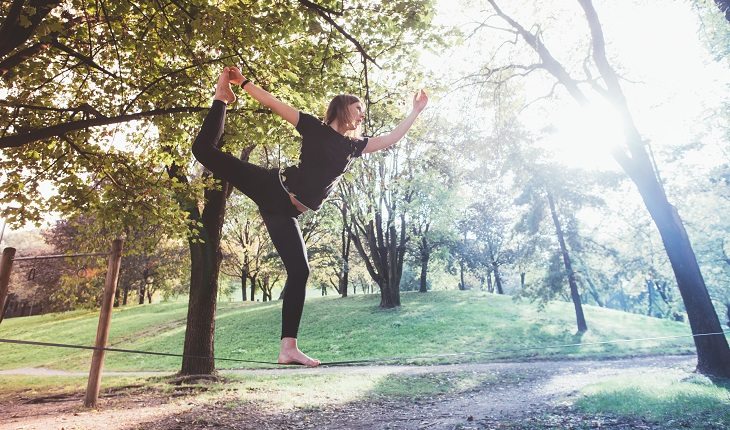 Slackline: mulher equilibrada segurando o pé