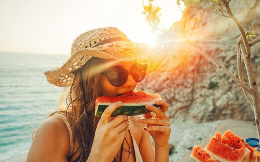 Mulher comendo melancia ao por do sol Boa alimentação no verão