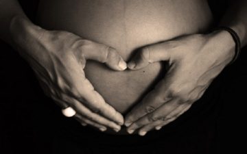 Mulher grávida com as mãos sobre sua barriga corrida durante a gravidez