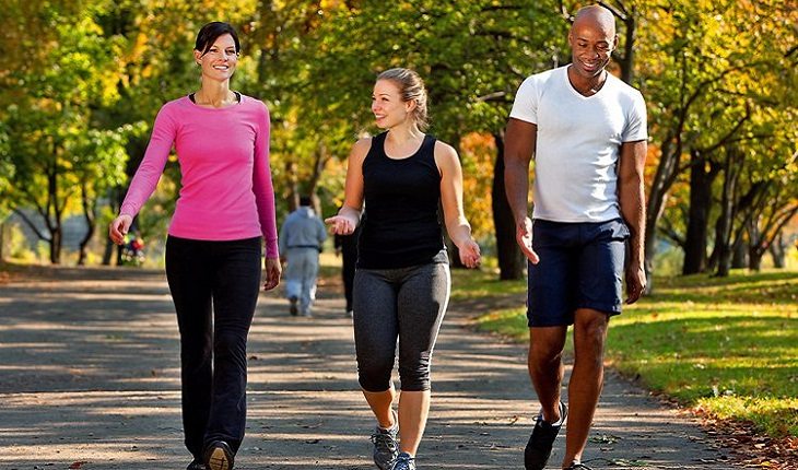 duas mulheres e um homem caminhando no parque