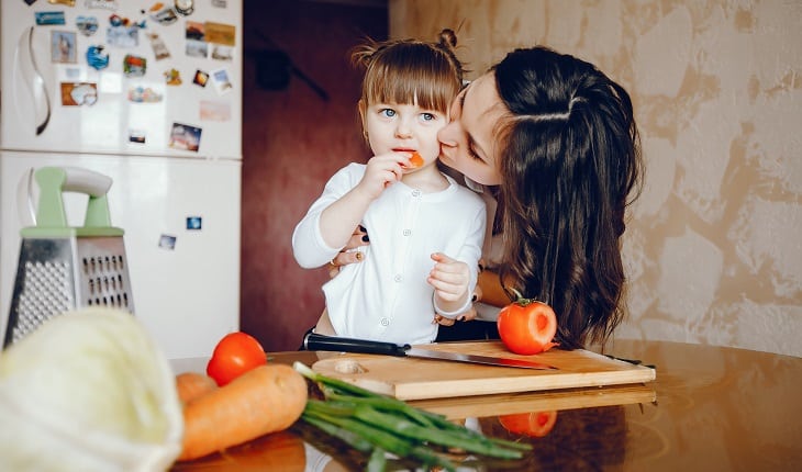 Alimentos nutritivos para as crianças: dicas para as férias de julho. Na foto, uma mãe com a filha cozinhando.