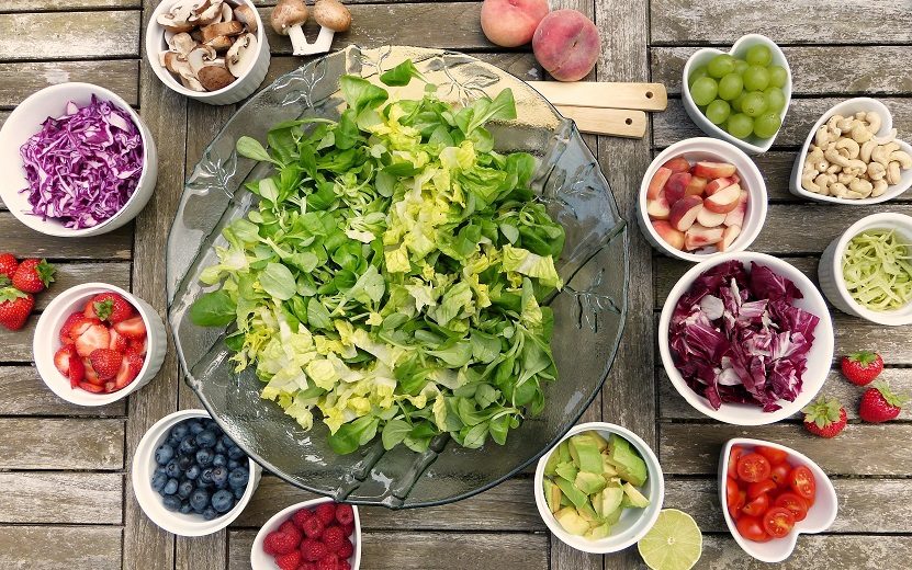 Alimentos ricos em nutrientes como saladas, frutas e verduras dispostos sobre um balcão. Os nutrientes são importantes dicas de alimentação para um organismo saudável