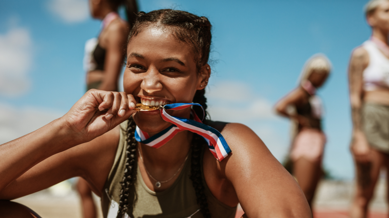 Imagem de atleta de corrida segurando a medalha na boca