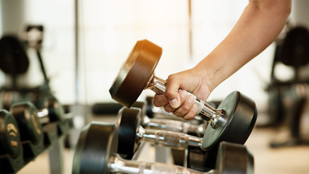 Mão segurando um haltere de academia, simbolizando treino de musculação e fortalecimento muscular.