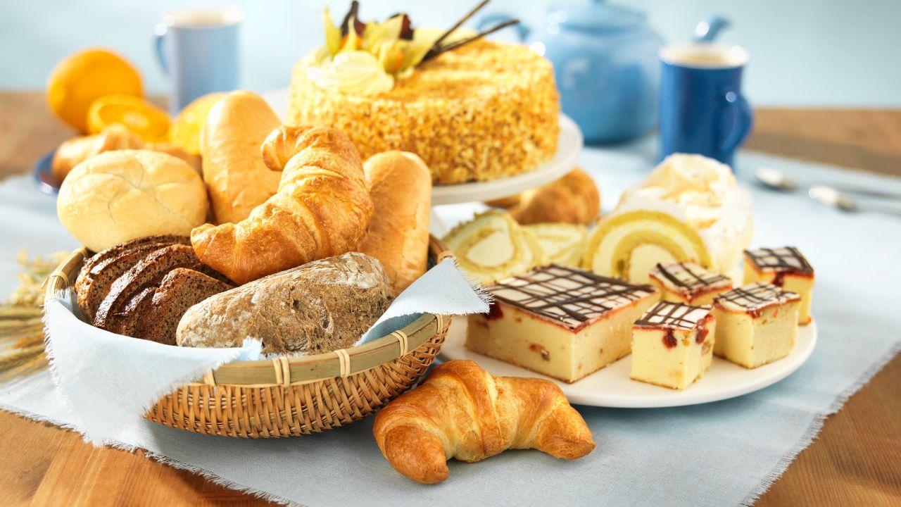 Mesa com pães, bolos e bolachas.