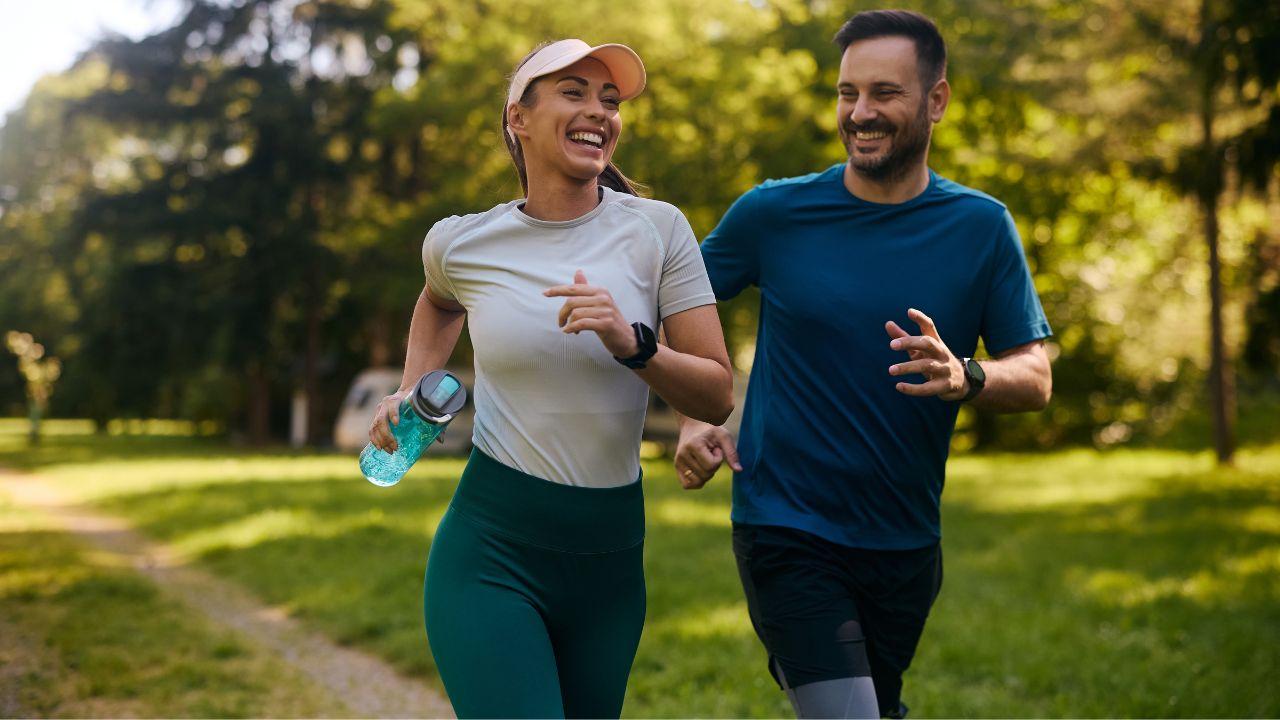 Mulher e homem com roupas fitness correndo num parque ao ar livre.