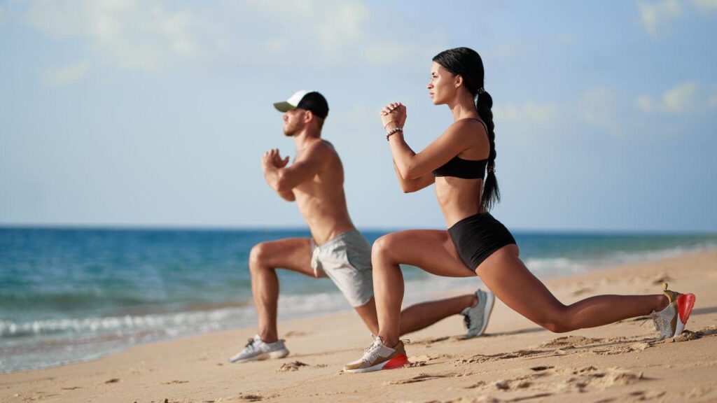 Imagem de uma mulher e um homem treinando na praia