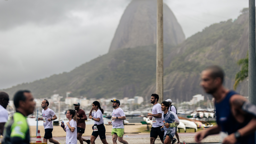 Pessoas correndo na meia maratona. Ao fundo, tem o morro do corcovado no Rio de Janeiro.