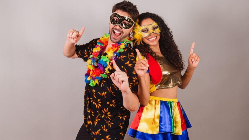 Mulher e homem encostados pelas costas usando máscaras e roupas de carnaval.