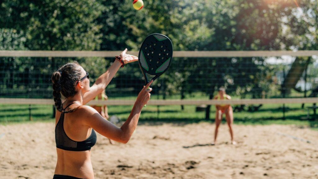 Mulheres de biquini jogando beach tennis.