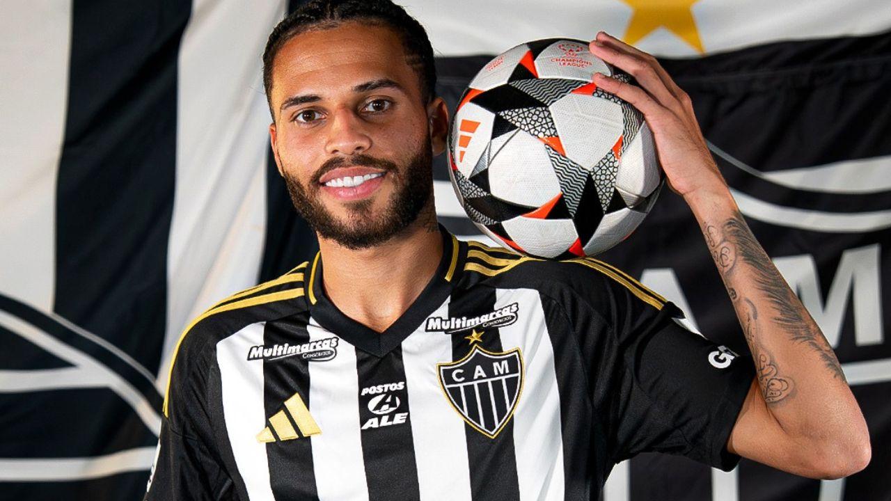 Jogador Alexsander. Homem negro, cabelo curto preto, uniforme do Atlético mineiro e ele segurando uma bola no ombro.