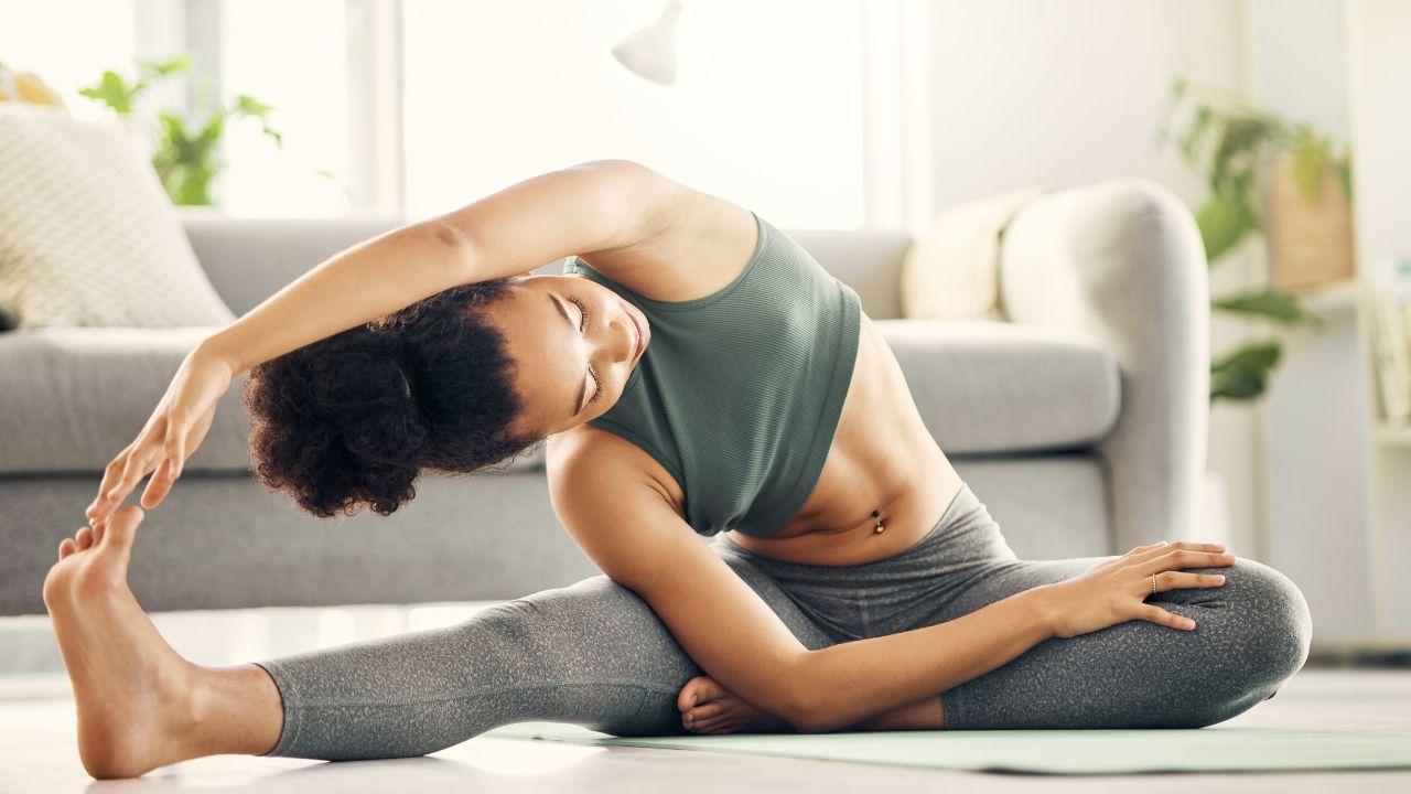 Foto mostra uma mulher fazendo alongamento lateral no colchonete.