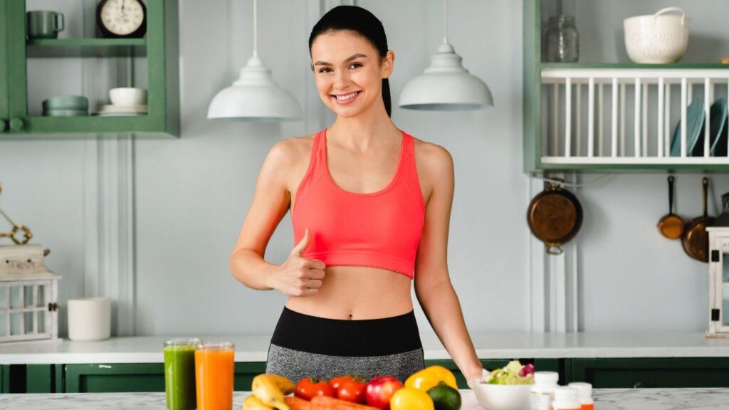 Imagem de uma mulher sorrindo com alimentos saudáveis na bancada da cozinha