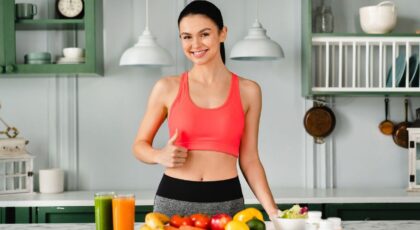 Imagem de uma mulher sorrindo com alimentos saudáveis na bancada da cozinha