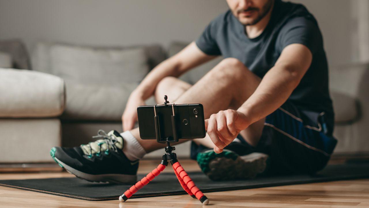 Imagem de um homem olhando o celular para começar o treino