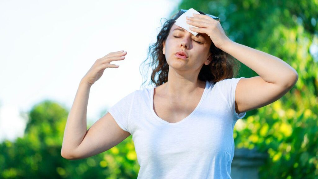 Imagem de uma mulher secando o suor com um papel branco