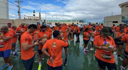 Pessoas usando camiseta laranja de corrida em pé ao ar livre.