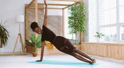 Mulher negra fazendo prancha lateral em um colchonete no chão.