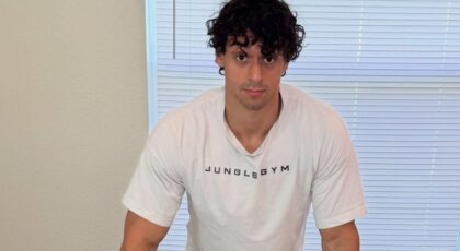 Victor Alexandre. Homem branco, jovem, cabelo curto castanho, usando camiseta branca e musculoso.