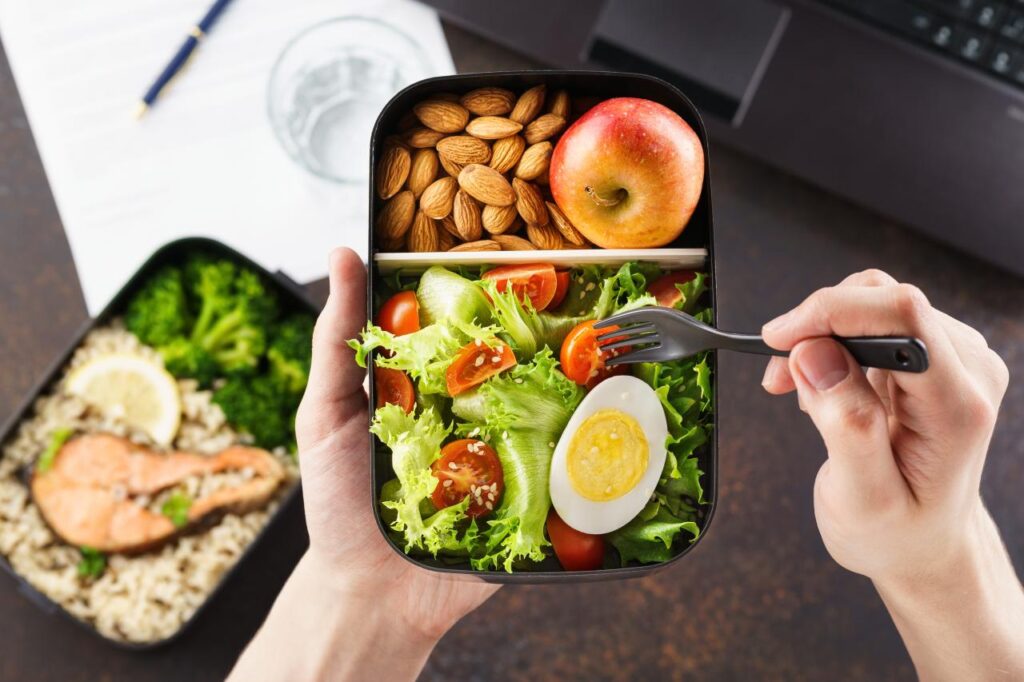 Foto mostra pessoa comendo marmita com ovo e verduras.