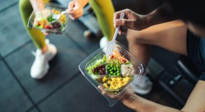 Imagem de duas pessoas comendo uma marmita com diferentes alimentos na academia