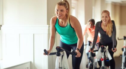 Mulheres na bicicleta em academia.