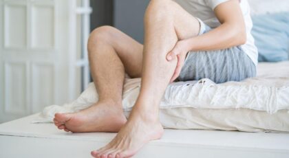 Imagem de uma pessoa com a mão na panturrilha na cama