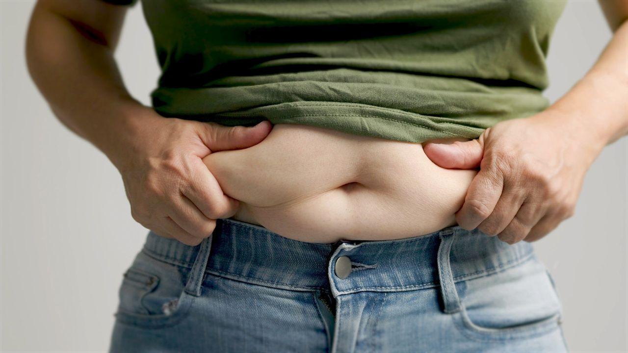 Imagem de uma pessoa apertando a gordura da barriga