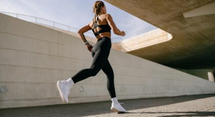 Mulher correndo ao ar livre usando legging e blusa preta.