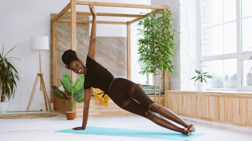 Imagem de uma mulher na posição de prancha lateral do Yoga