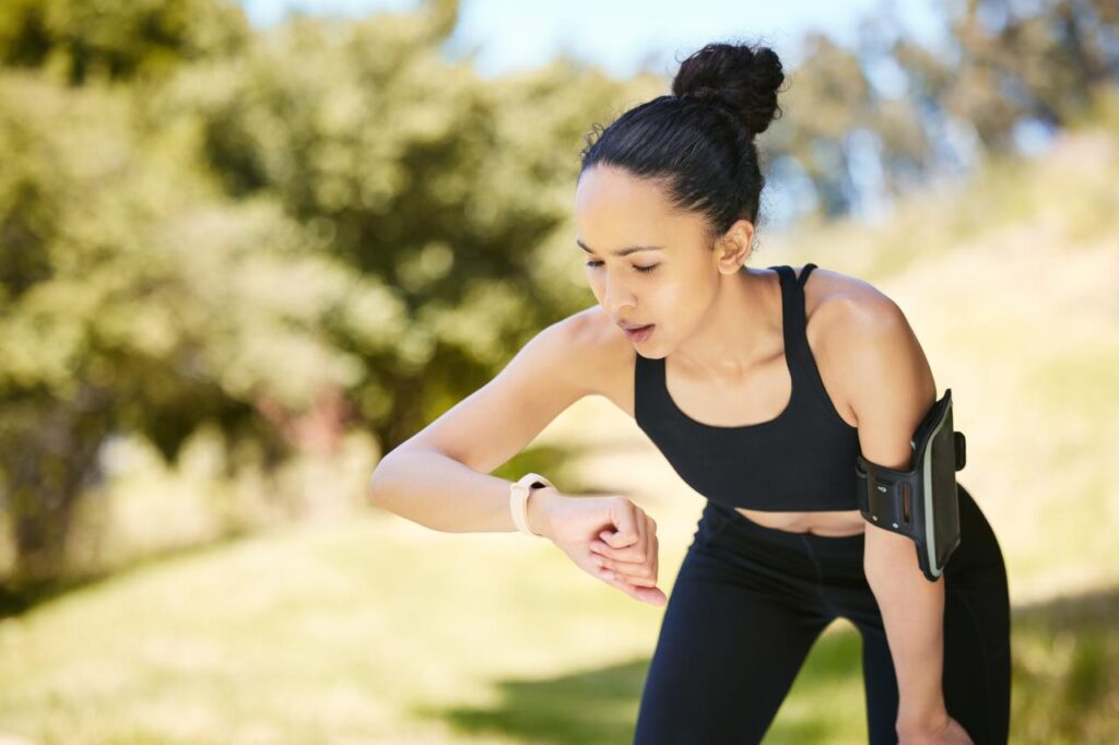 Mulher com roupa de exercício físico vendo o smartwatch.