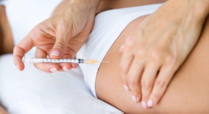 Imagem de uma pessoa aplicando produto com uma seringa na lateral do glúteo de uma mulher