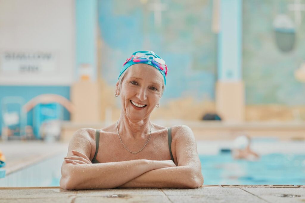 Mulher idosa sorrindo dentro da piscina fazendo natação.