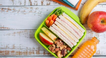 Foto mostra lanches de pães e frutas dentro de um potinho.