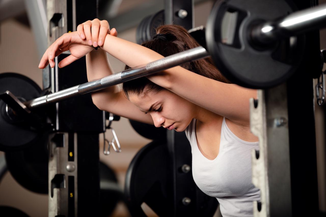 Mulher cansada após fazer musculação.