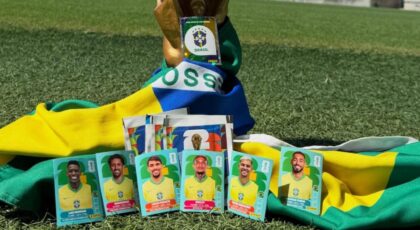 Imagem das figurinhas da Copa encostadas em uma bandeira do Brasil e na taça da Copa no estádio