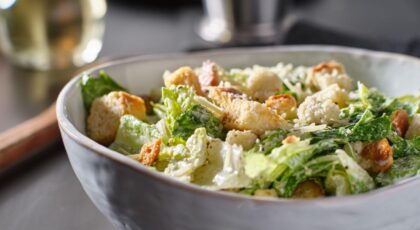 Imagem de um pote grande com salada de folhas e frango