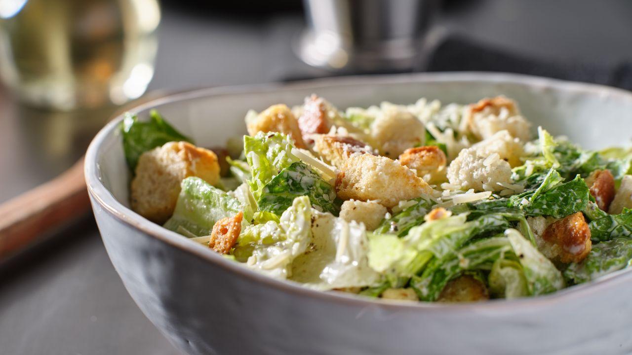 Imagem de um pote grande com salada de folhas e frango