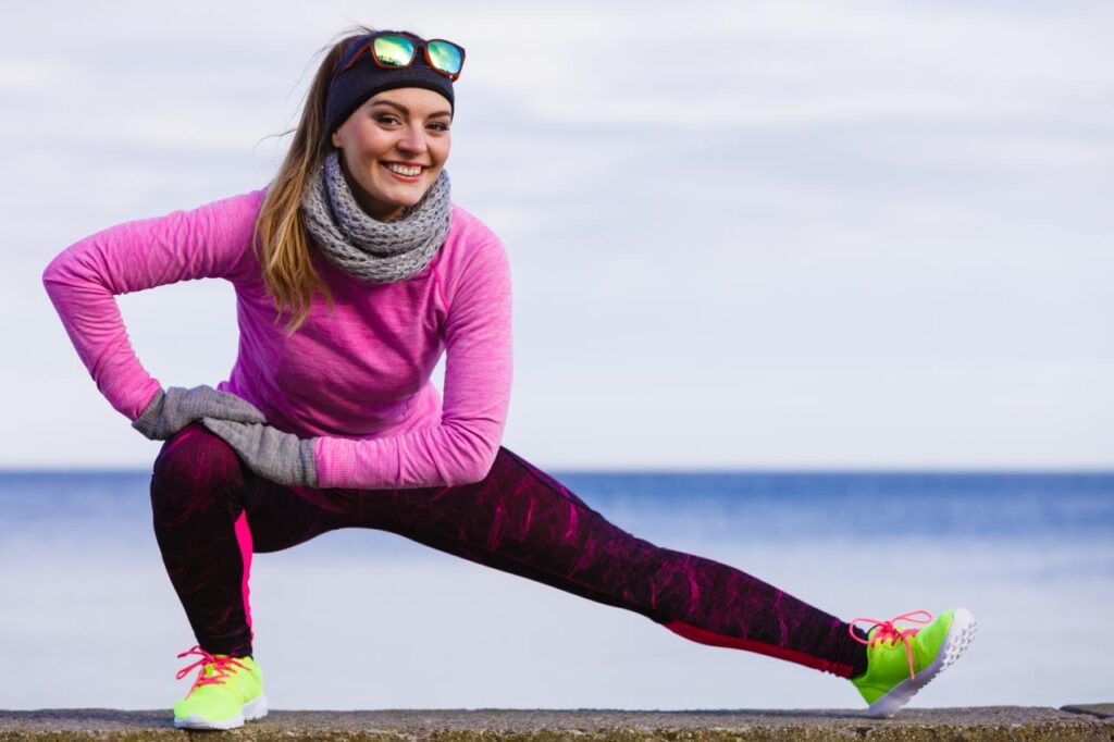Mulher com roupa de frio fazendo exercício ao ar livre.