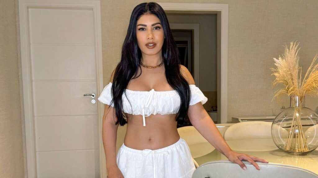 Simaria usando vestido cropped e saia branca ao lado de um mezanino.