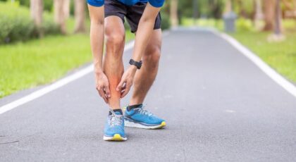 Imagem de um homem com a mão na canela durante a corrida