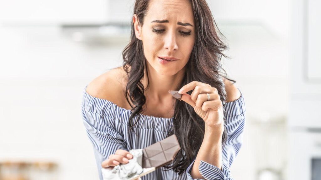 Imagem de uma mulher tentando não comer chocolate