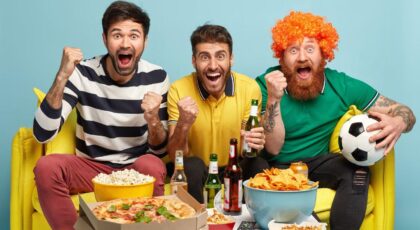 Imagem de homens torcendo e comendo besteiras