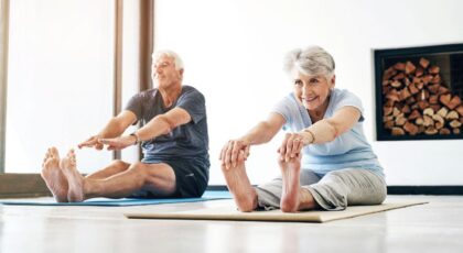 Imagem de dois idosos fazendo exercício de pilates se alongando para frente