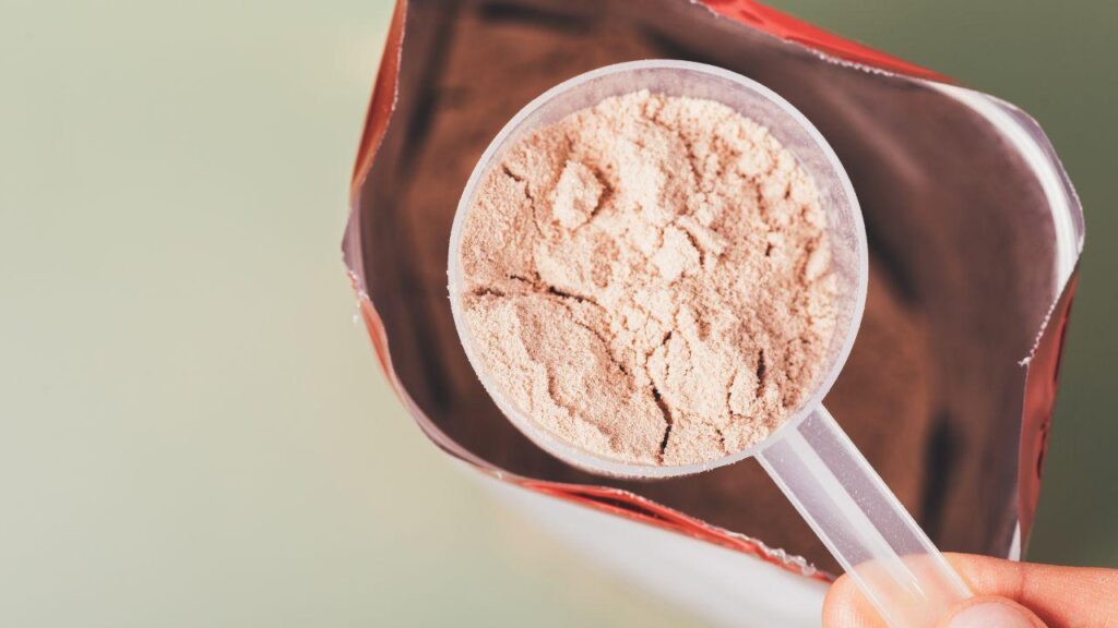 Imagem de uma pessoa pegando um scoop de whey protein do pacote